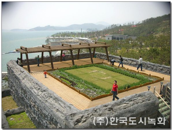 고성공룡엑스포 주제관 옥상녹화 시공사례 — 파고라와 정형 식재 구획, 바다 전망 (경남 고성)